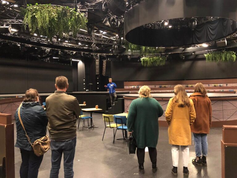 Bezoekers met een gids in een lege tv-studio op het Media Park